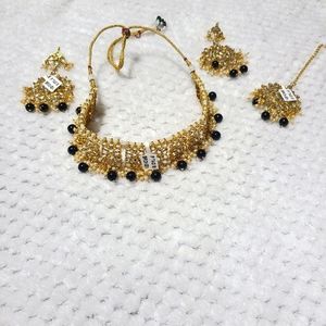 Indian jewelery choker set with black and golden choker, earings, and tikka.